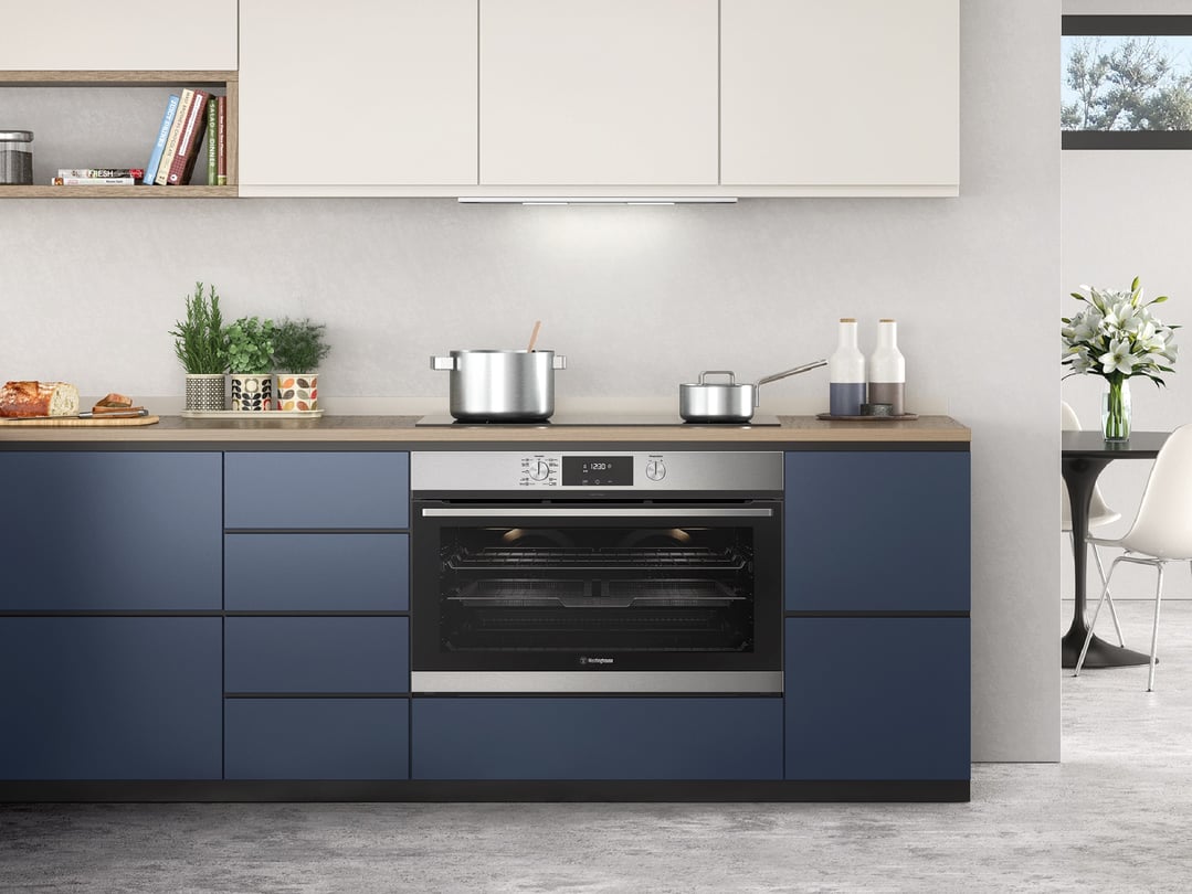 Built-in oven and cooktop in a modern kitchen with blue cabinets and wooden countertop