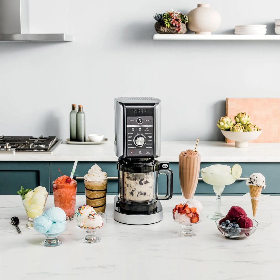 Ninja CREAMi Deluxe 11-In-1 Ice Cream Maker on a kitchen counter with desserts