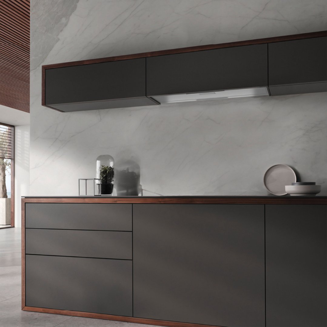 A slideout rangehood integrated into dark kitchen cabinetry with a marble backsplash
