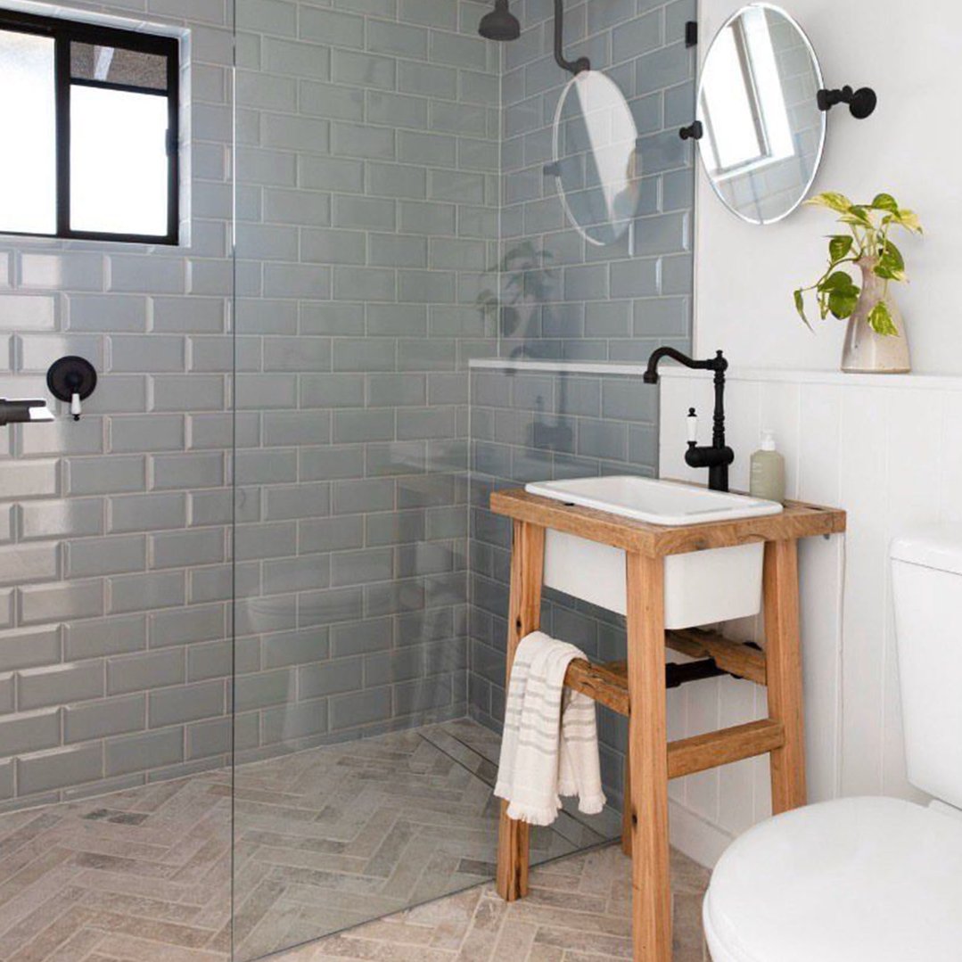 Fireclay sink on a wooden stand in a modern bathroom with subway tiles