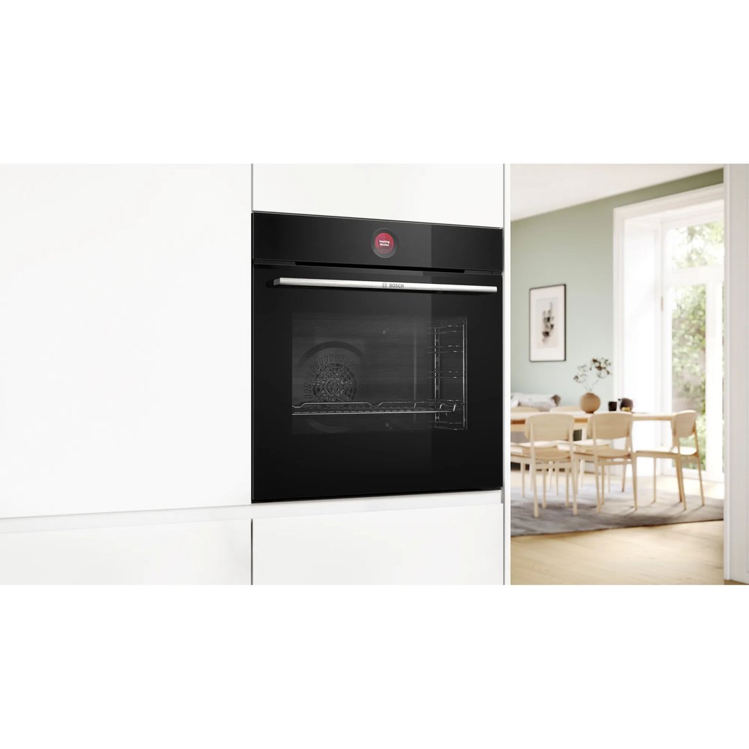 Black built-in Bosch oven in a white kitchen with a dining room in the background