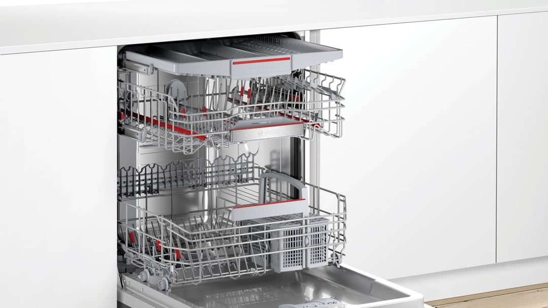 Open Bosch Series 6 built-under dishwasher with empty racks in a white kitchen