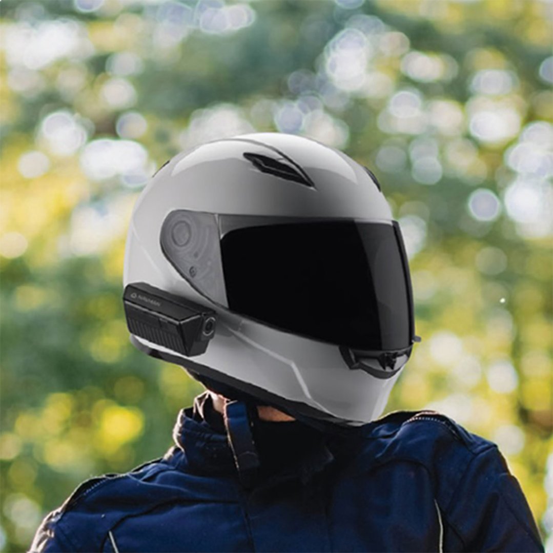 A person wearing a white motorcycle helmet with a dash cam attached to the side