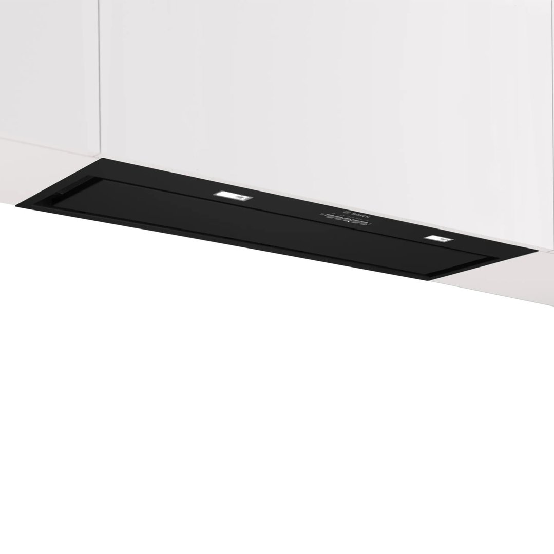 Black integrated rangehood installed under white cabinetry in a kitchen setting