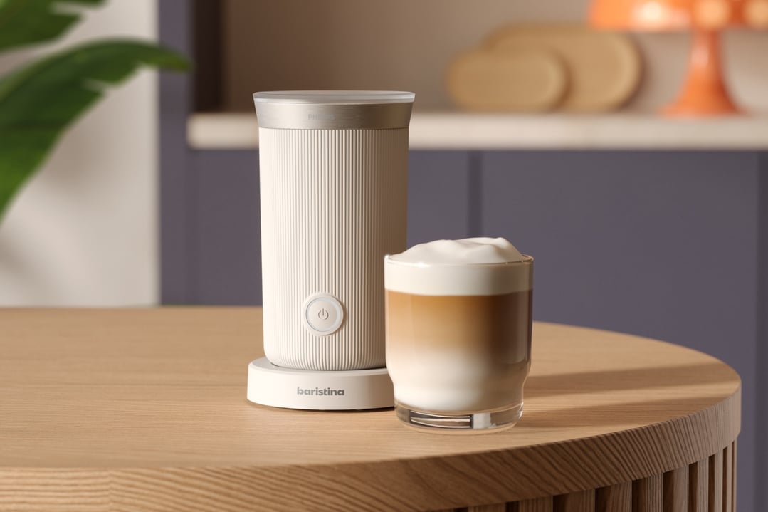 Philips Baristina Milk Frother and a glass of latte on a wooden table