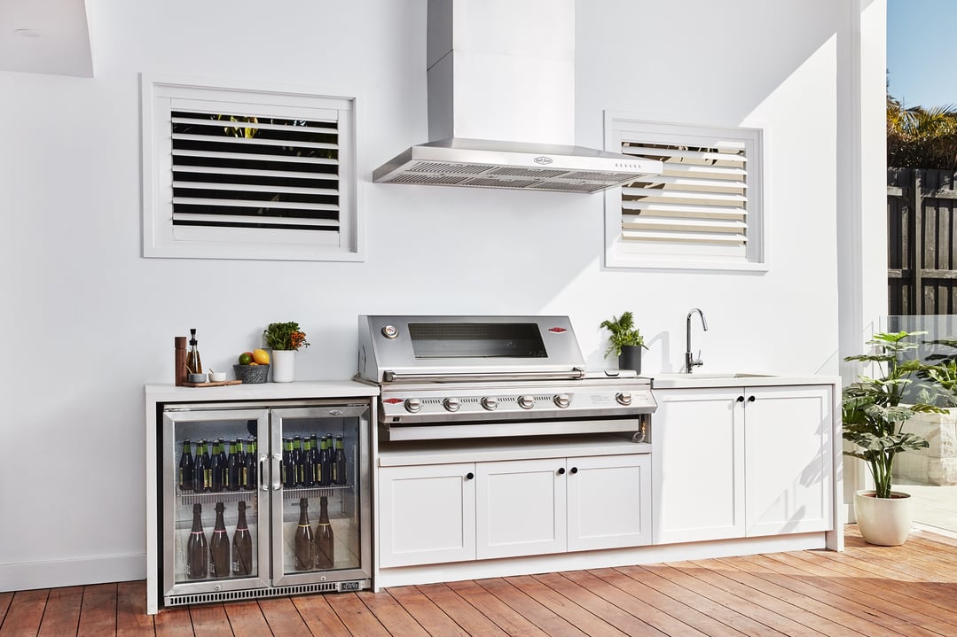 Stainless steel outdoor canopy hood above a barbecue grill and drinks fridge