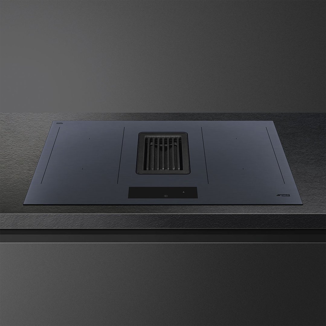 Integrated induction cooktop with downdraft extractor fan on a dark countertop