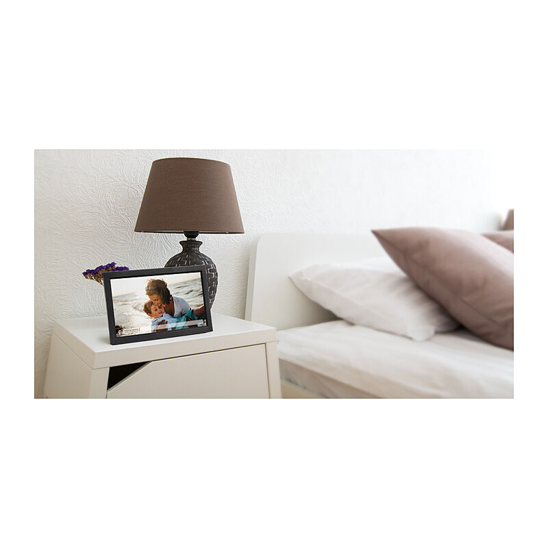 NIVO digital photo frame displaying a photo, on a bedside table in a bedroom