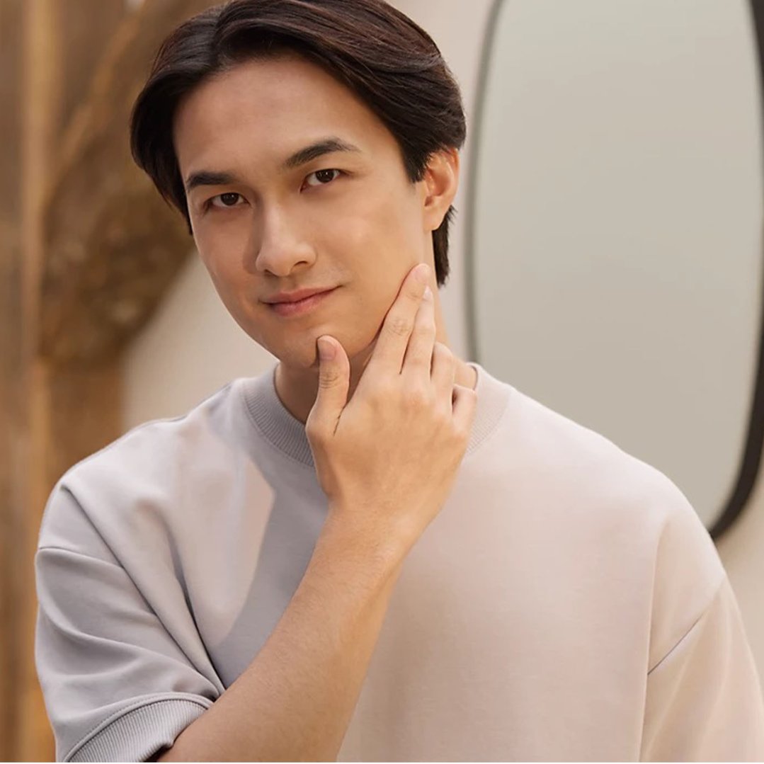 Man touching his jawline, looking at the camera, in a light-colored shirt