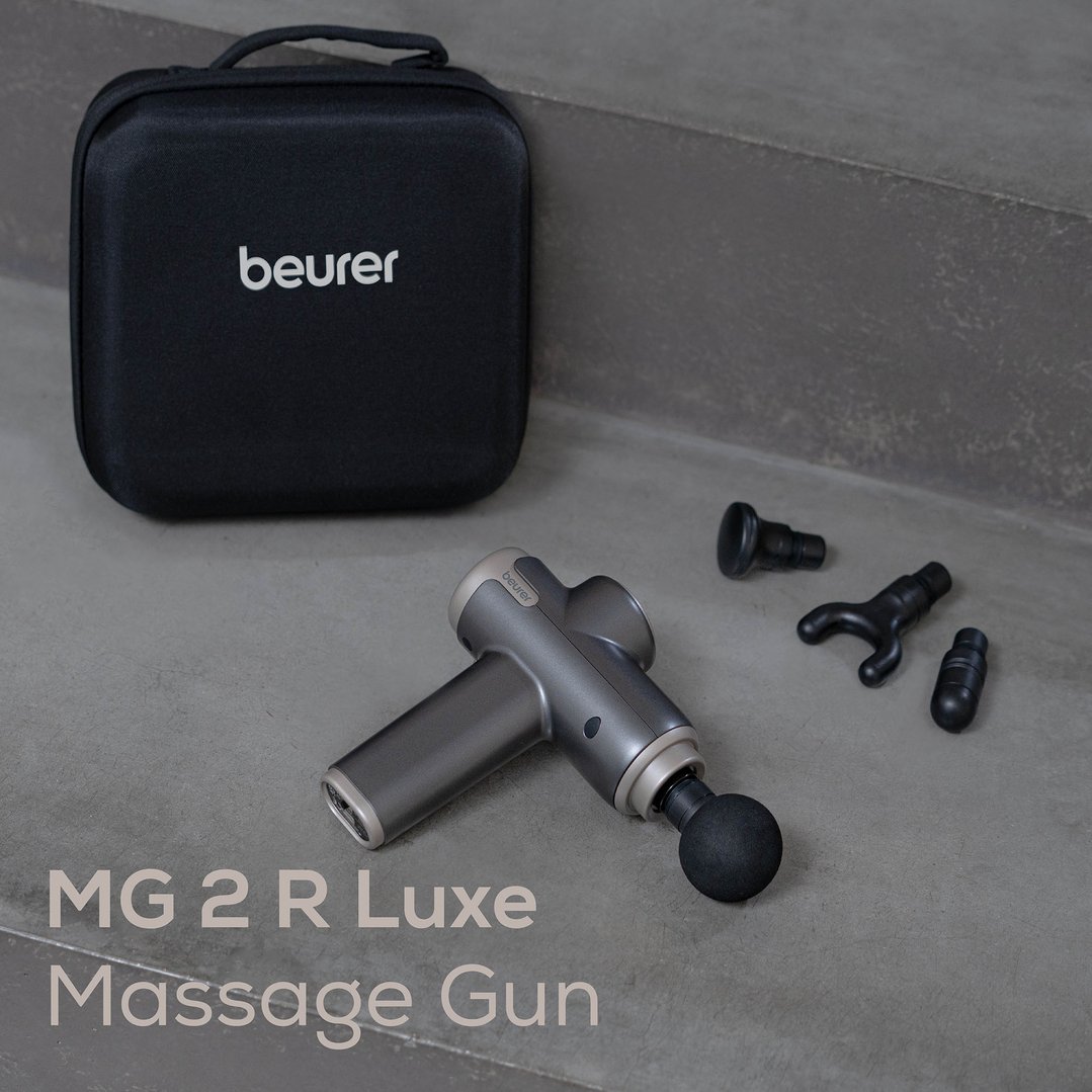 Beurer compact massage gun and accessories on a concrete surface with a carrying case