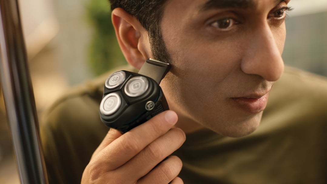 Man using a Philips electric shaver to trim his sideburns