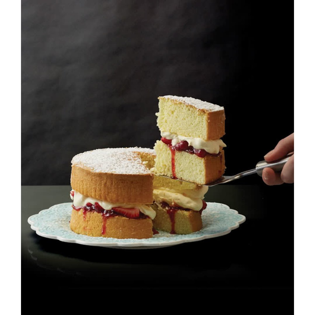 A hand using a Carveasy Twin Blade to serve a slice of cake