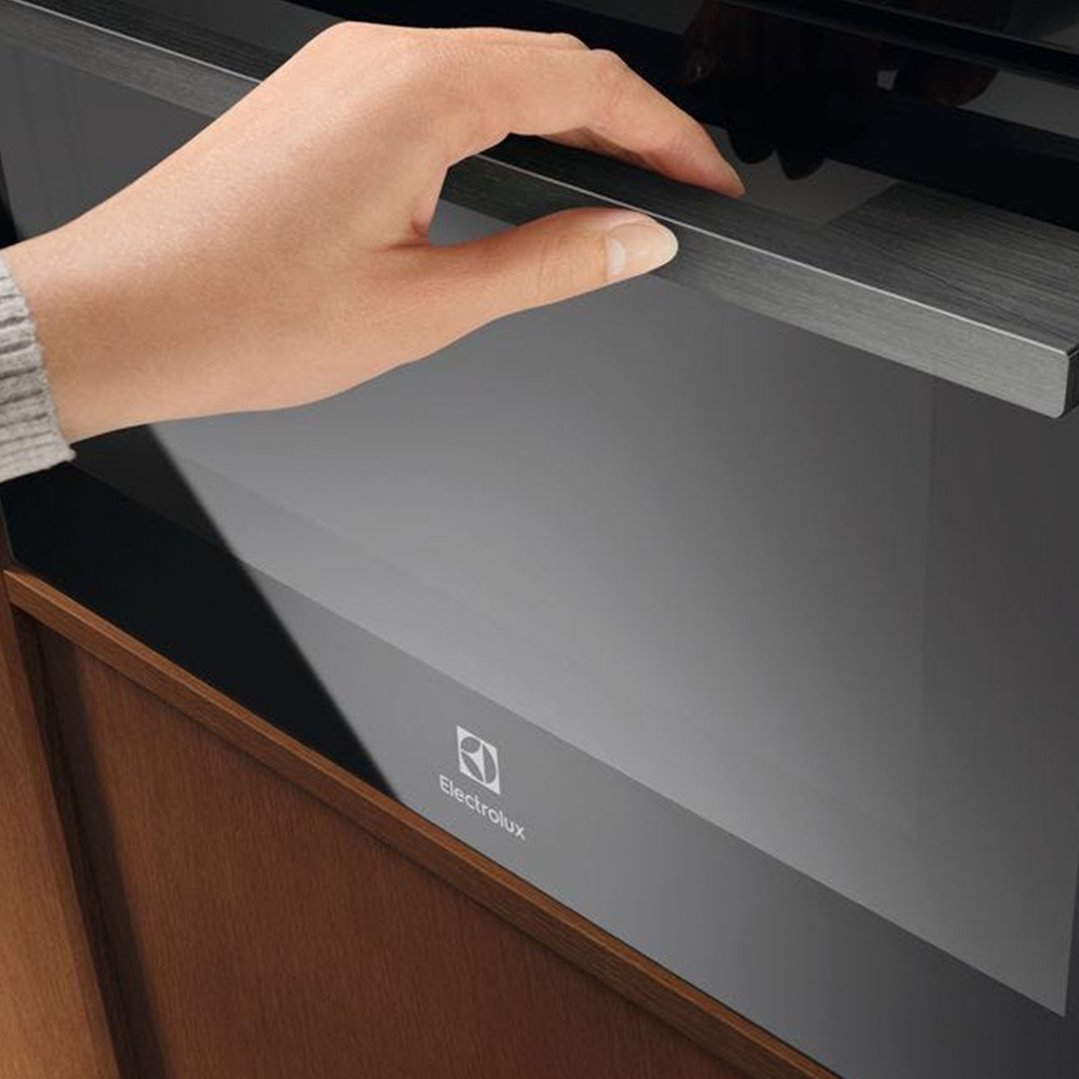 Hand opening the door of a black built-in Electrolux microwave oven