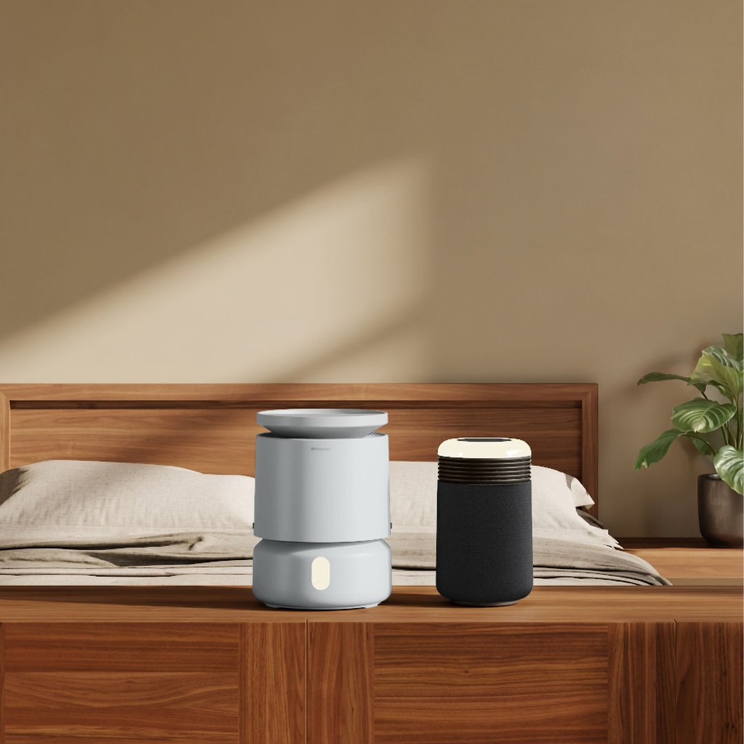 Two air purifiers on a wooden bedside table in a bedroom