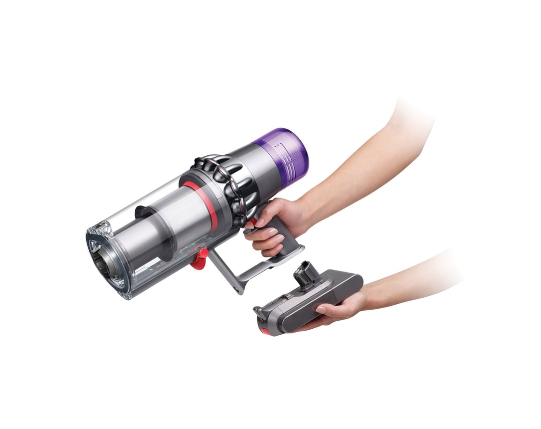 Hands holding a Dyson V11 stick vacuum and a cleaning head attachment