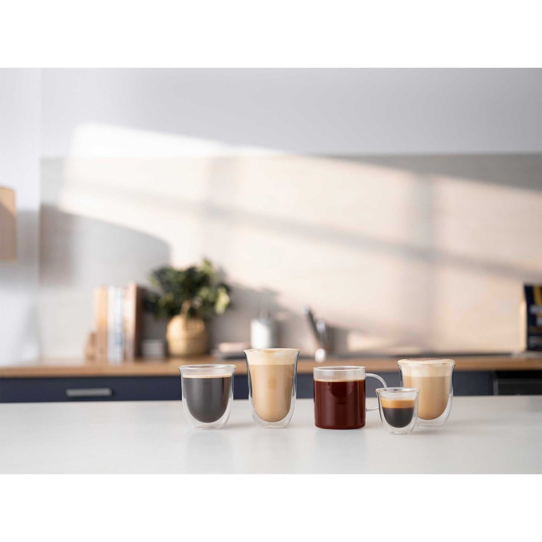 Five different coffee drinks in glass cups on a white kitchen counter