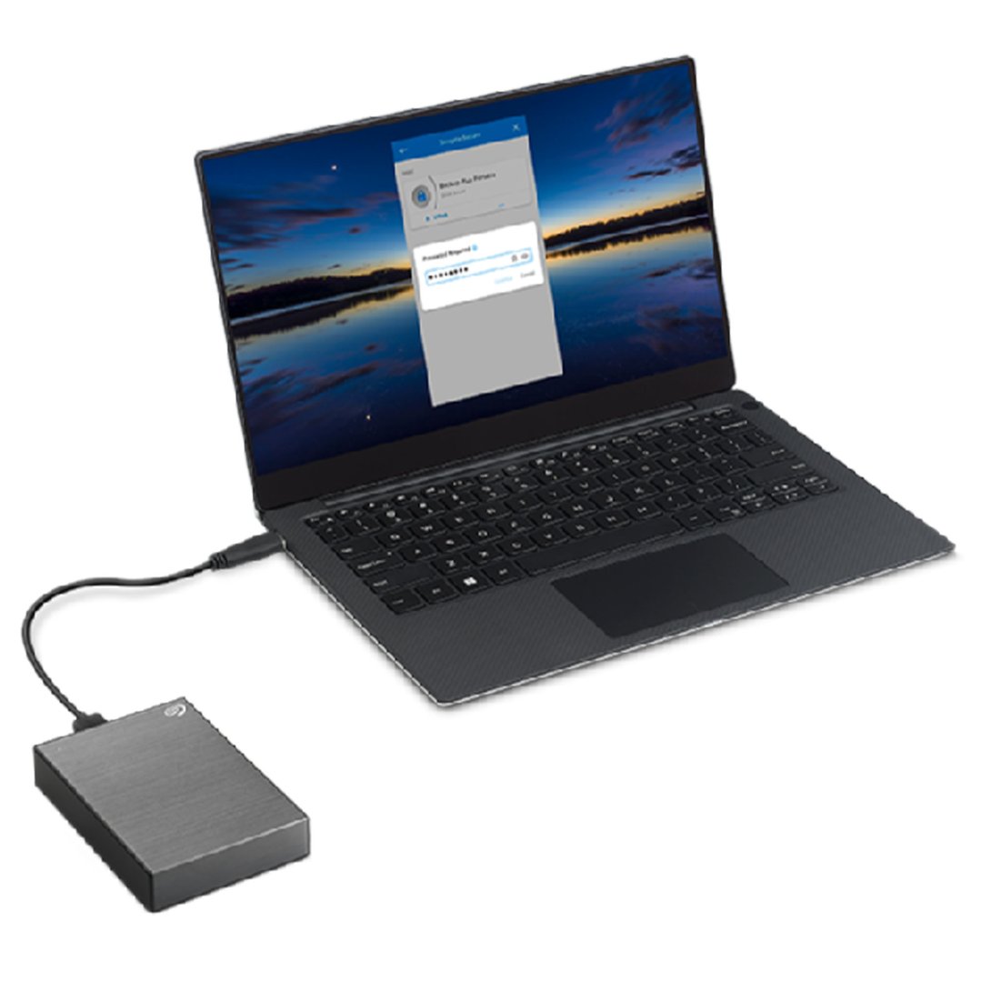 Grey external hard drive connected to a laptop displaying a login screen