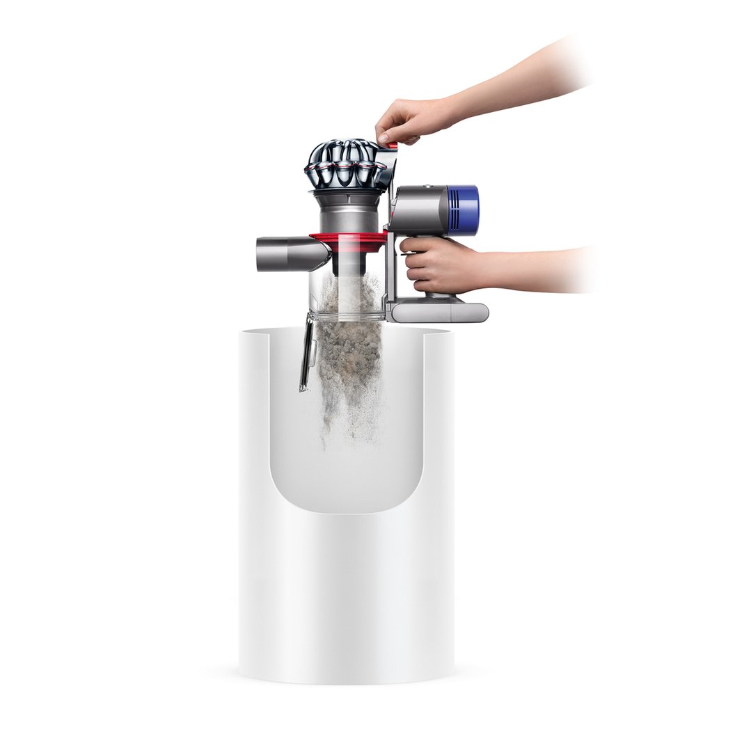 Hands emptying the Dyson V8 Animal Handstick Vacuum into a white bin