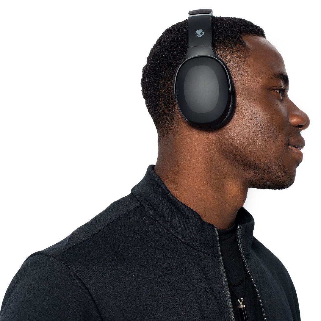 Man wearing black Skullcandy Crusher Evo headphones, side profile on white background