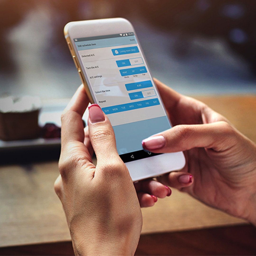 Hands holding a smartphone displaying the WiFi Air Conditioner Controller app interface