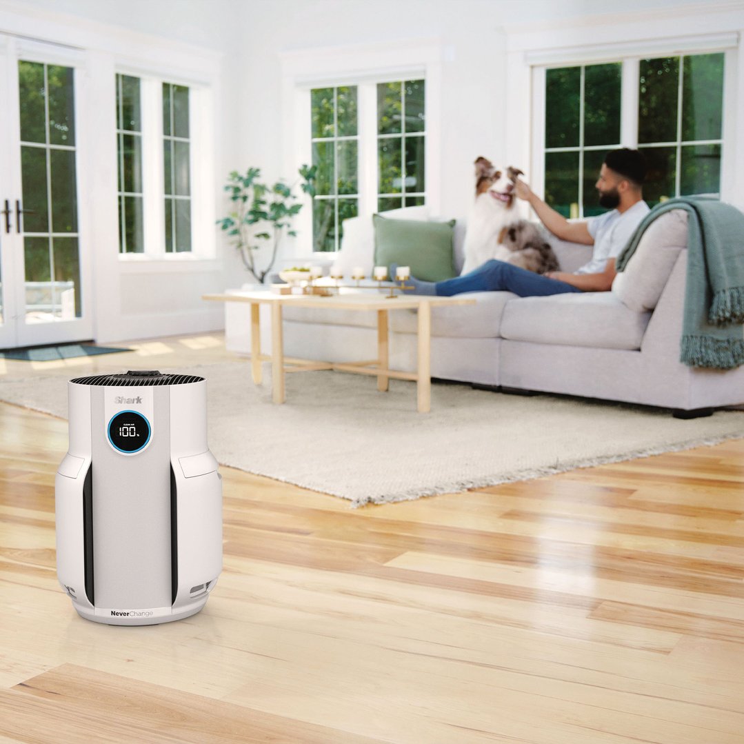 SHARK air purifier on a wooden floor in a living room with a man and dog