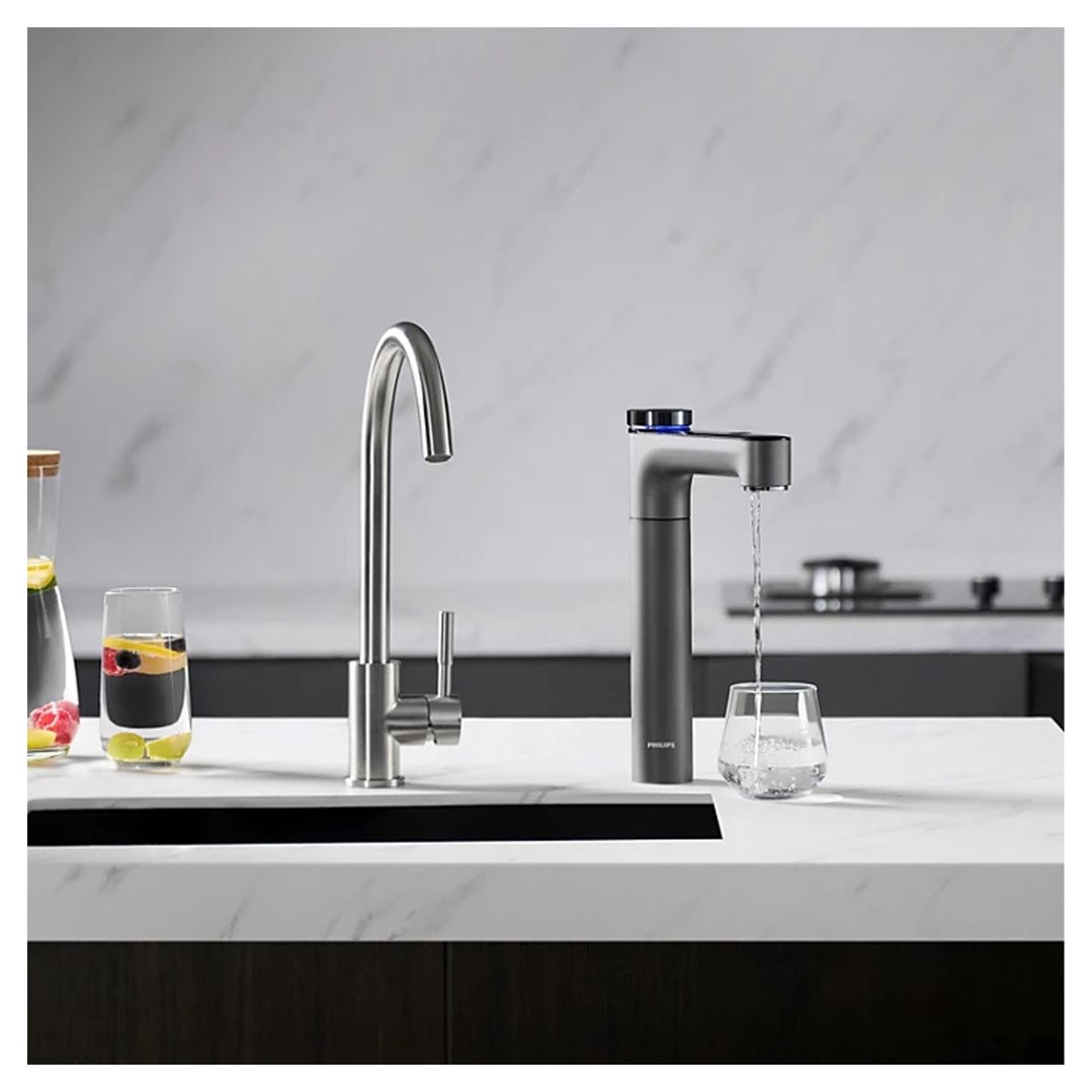 Philips water tap station dispensing water into a glass on a kitchen counter