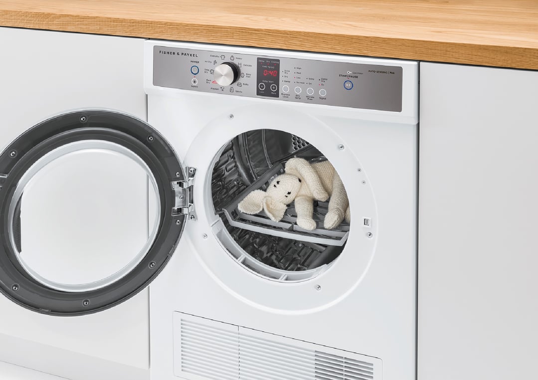 White vented dryer with door open, showing a knitted toy inside