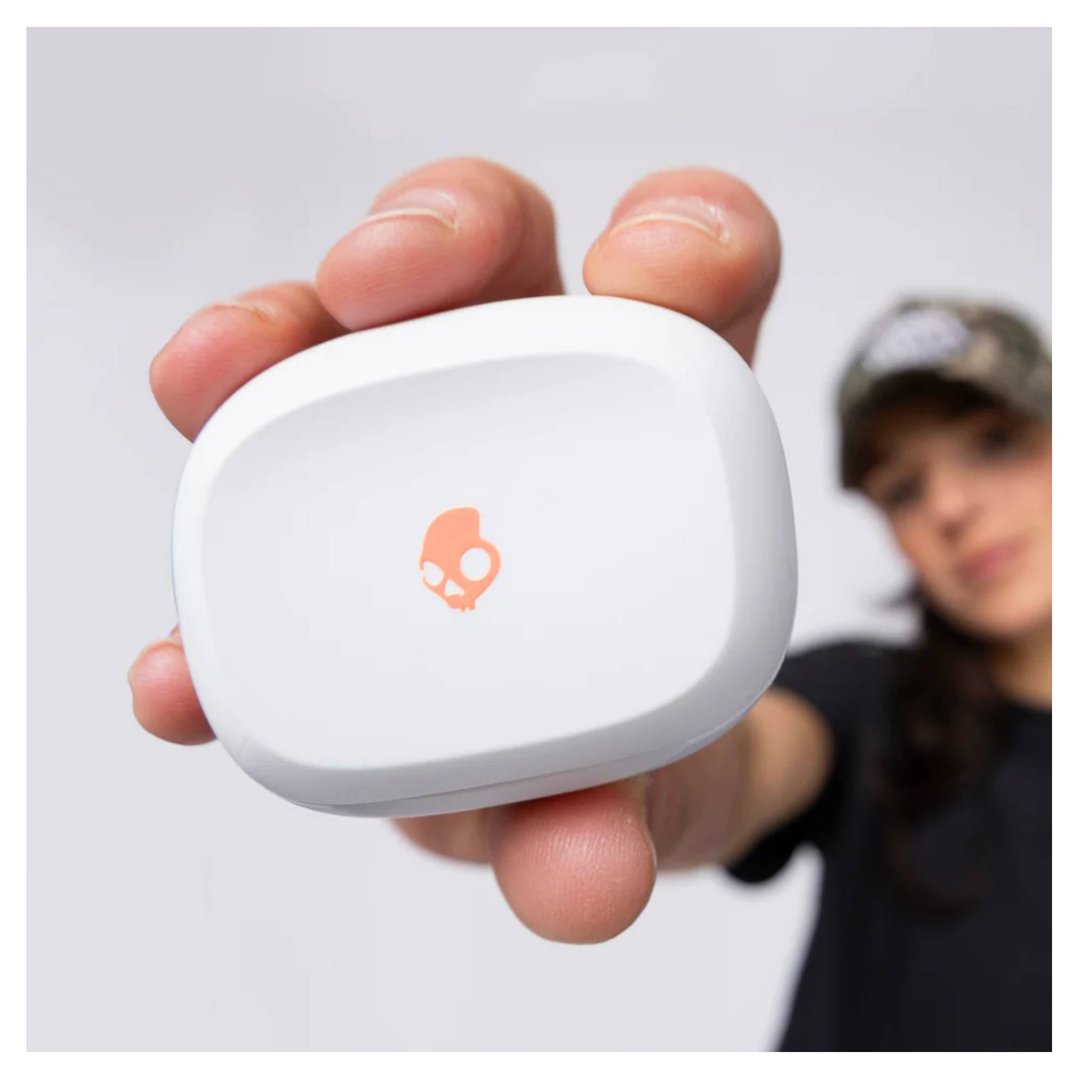 Hand holding a white Skullcandy Smokin Buds TWS in-ear case with orange logo
