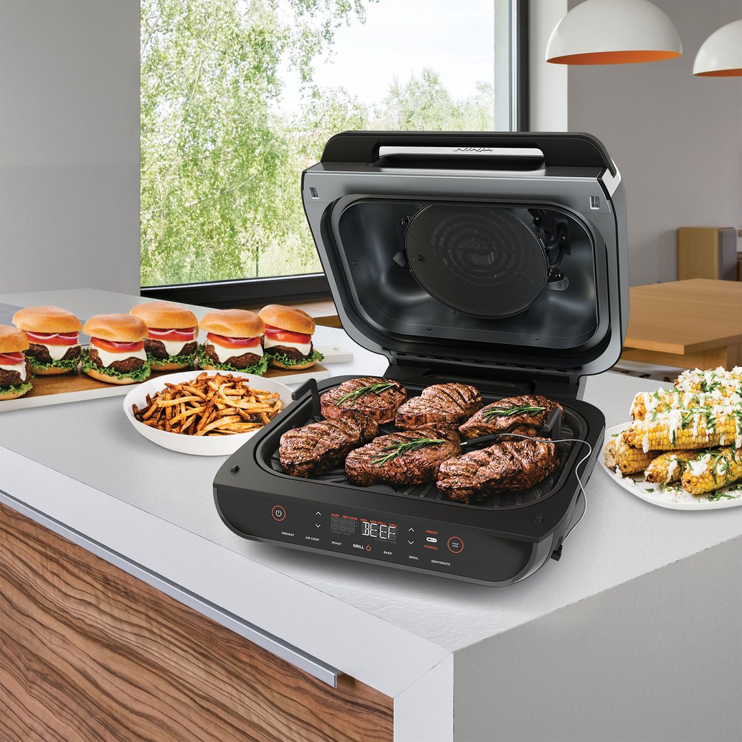 Ninja Foodi Smart XL Grill & Air Fryer grilling steaks with sides on a counter