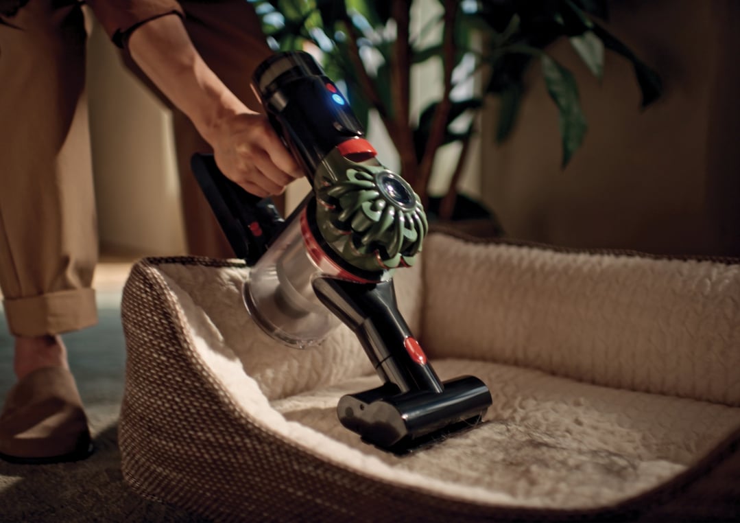 Person using a handStickVacuum to clean a pet bed