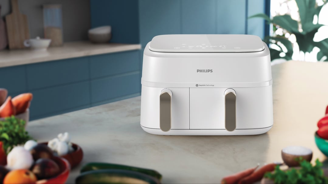 White Philips dual basket airfryer on a kitchen counter with vegetables