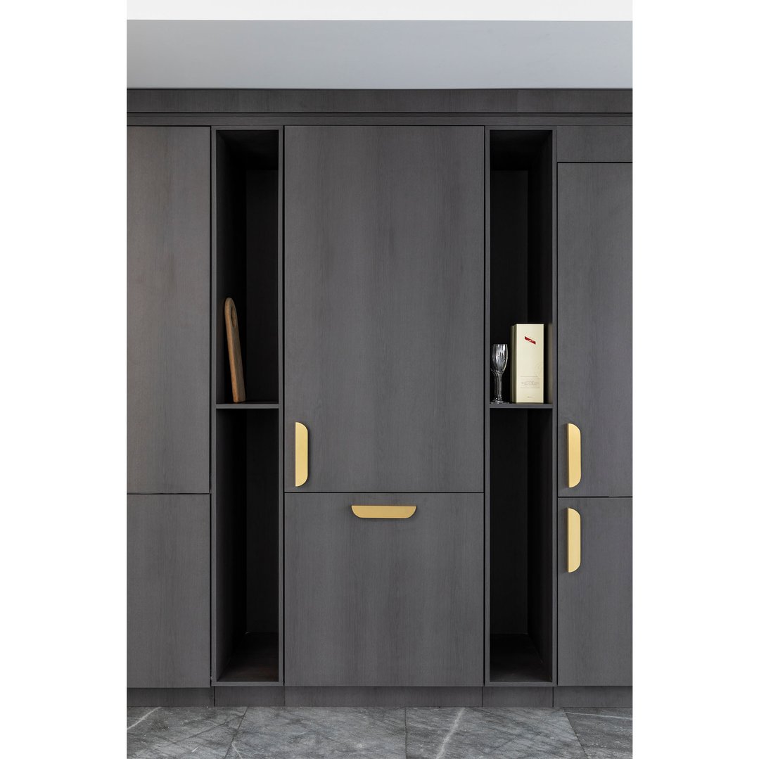 Integrated bottom mount fridge with dark wood paneling and gold handles in a kitchen