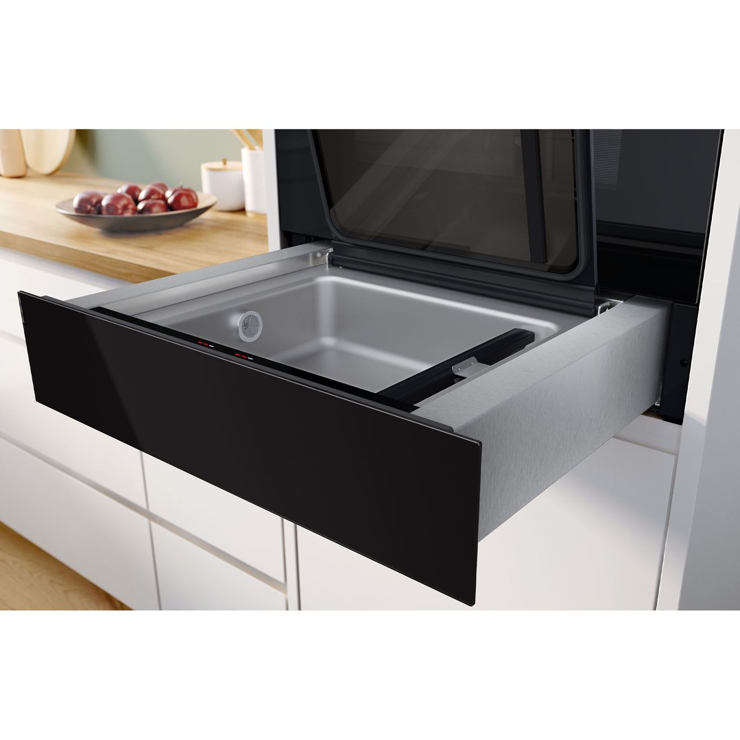 Black vacuum drawer pulled out in a kitchen with fruit on the counter