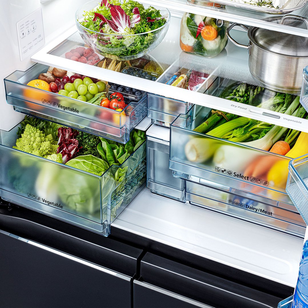 Open French door fridge interior filled with fresh vegetables and fruits