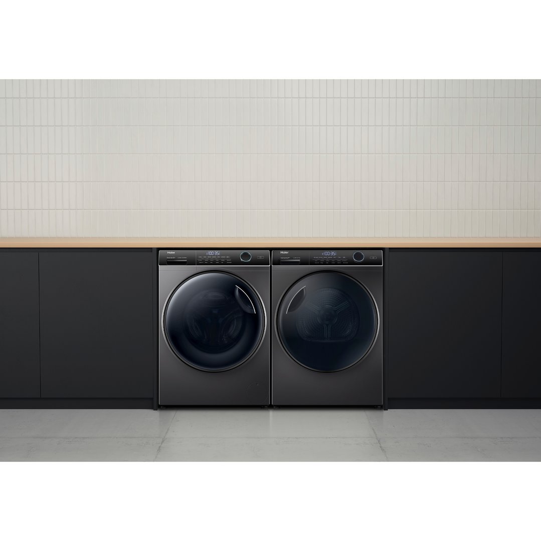 Two dark washing machines in a modern laundry room with light tiles