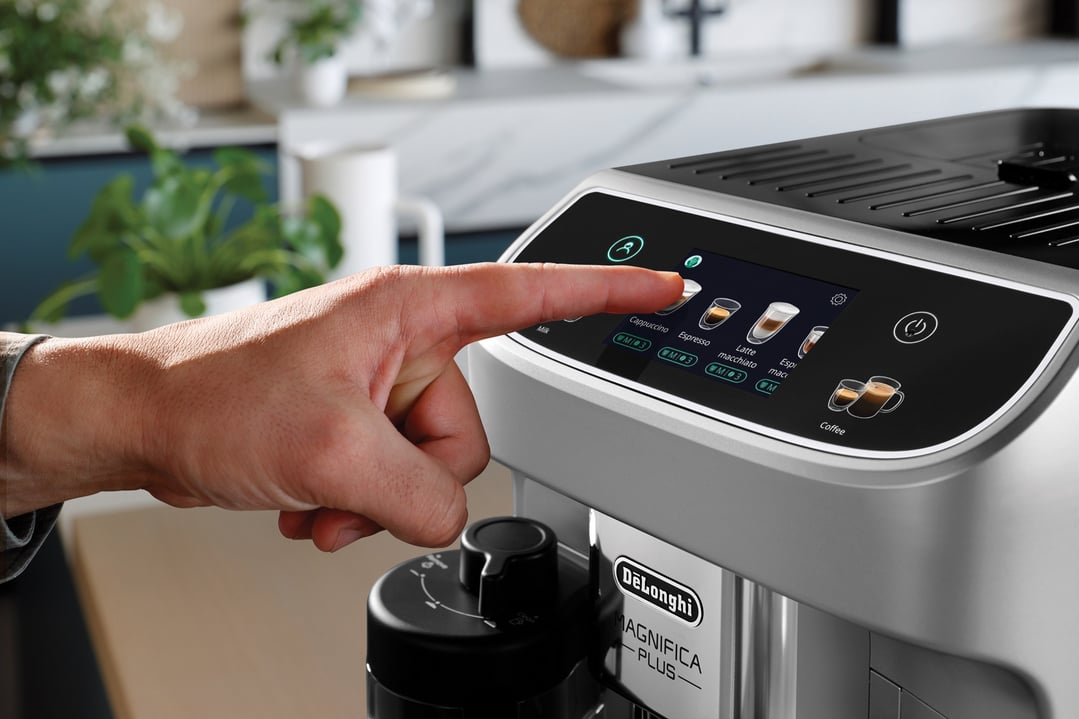 Hand selecting a drink on the screen of a coffee machine