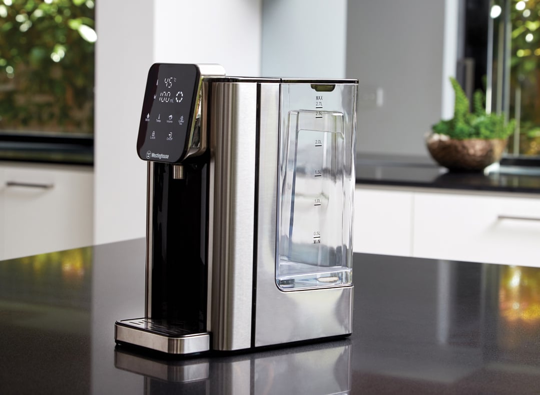 Instant hot water dispenser on a dark countertop in a modern kitchen