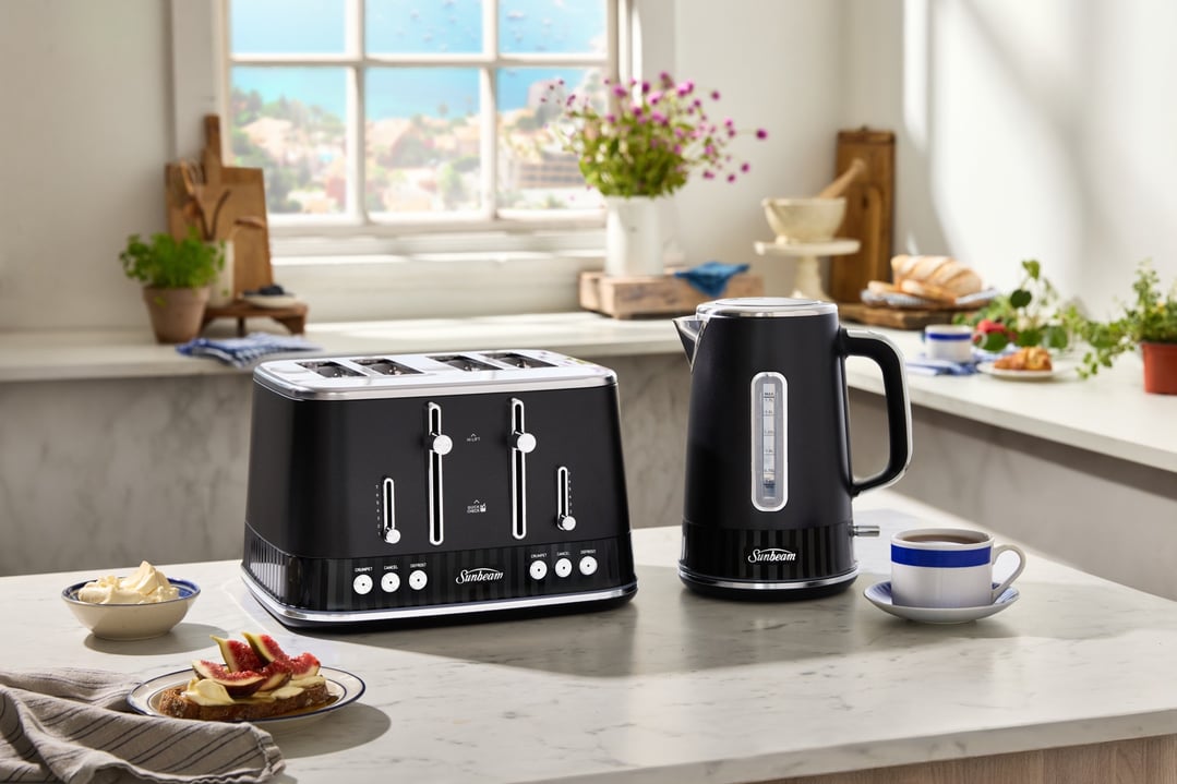 Black kettle and 4-slice toaster on a kitchen counter with food and drinks