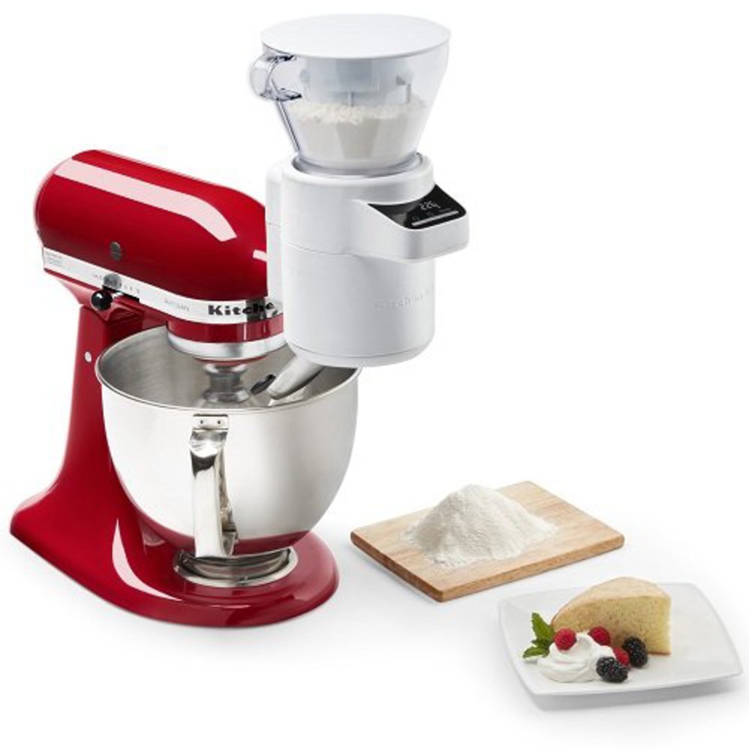 Red stand mixer with a white sifter and scale attachment, with flour and cake
