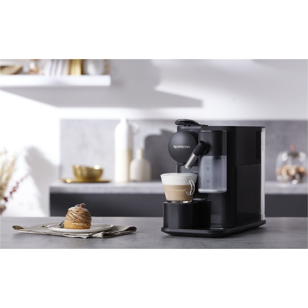 Black DELONGHI coffee machine making a latte, with a pastry on a counter