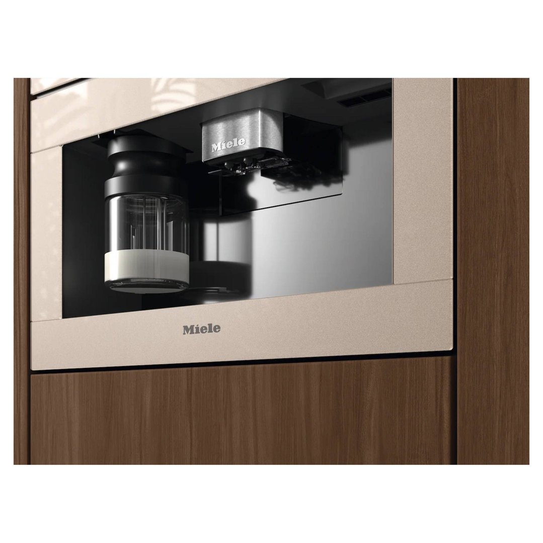 Built-in coffee machine with milk container in a dark wood kitchen cabinet