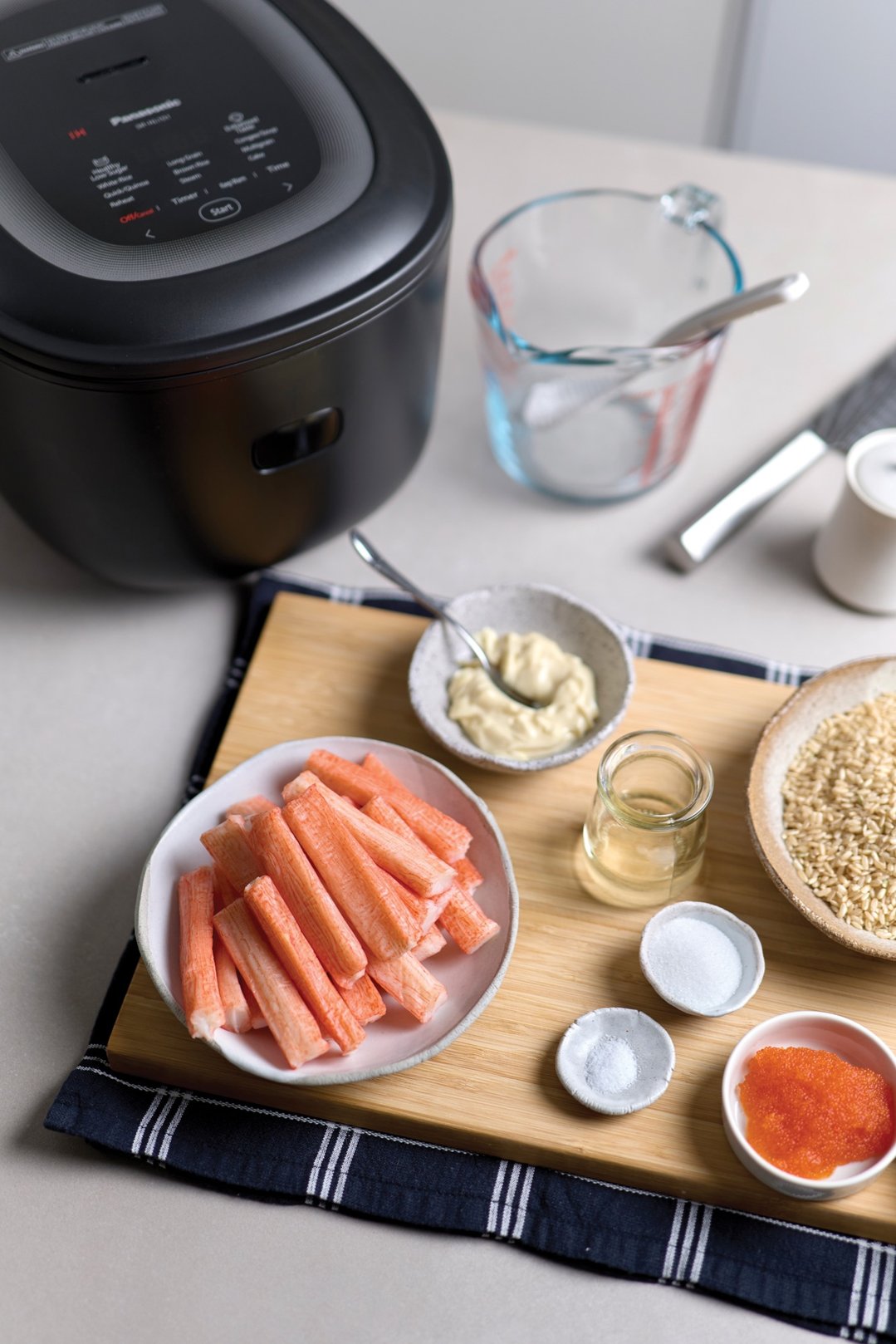 Panasonic rice cooker on a counter with ingredients for a meal