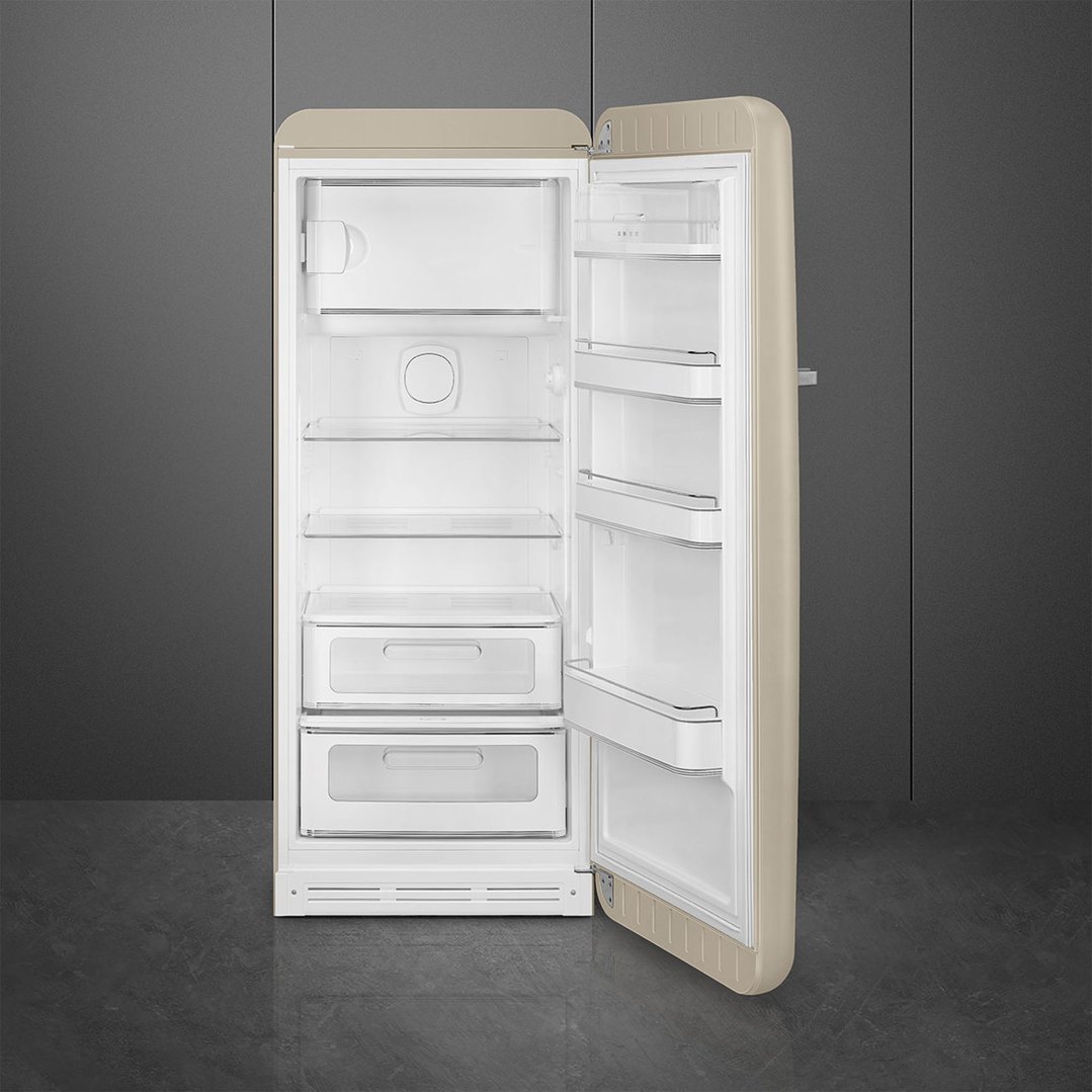 Open pale beige retro refrigerator with interior shelves and drawers in a room