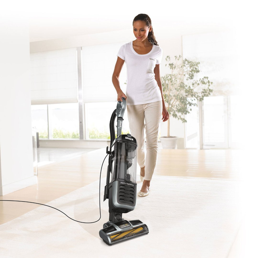 Woman using a Shark Navigator Pet Vacuum on a carpeted floor