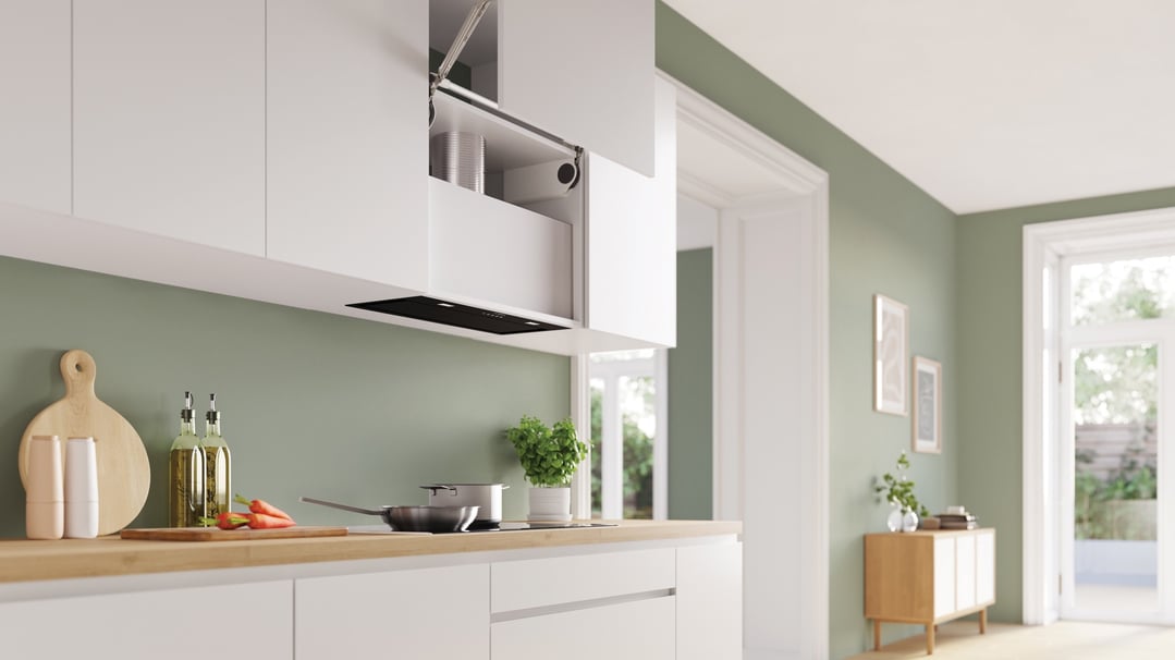 Integrated rangehood in a modern kitchen with white cabinets and green walls