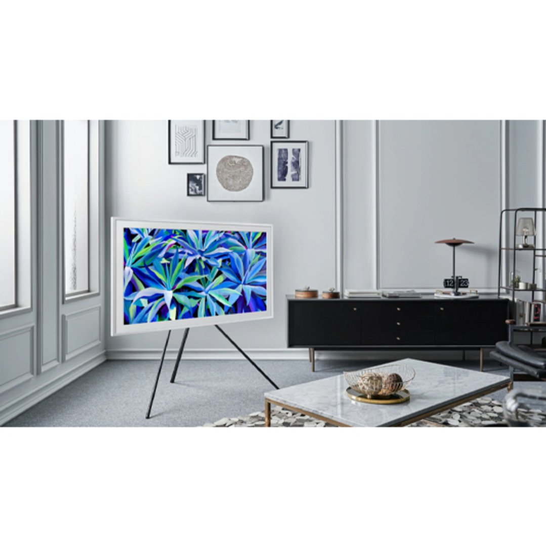 A white Samsung TV on a stand displaying blue foliage in a living room