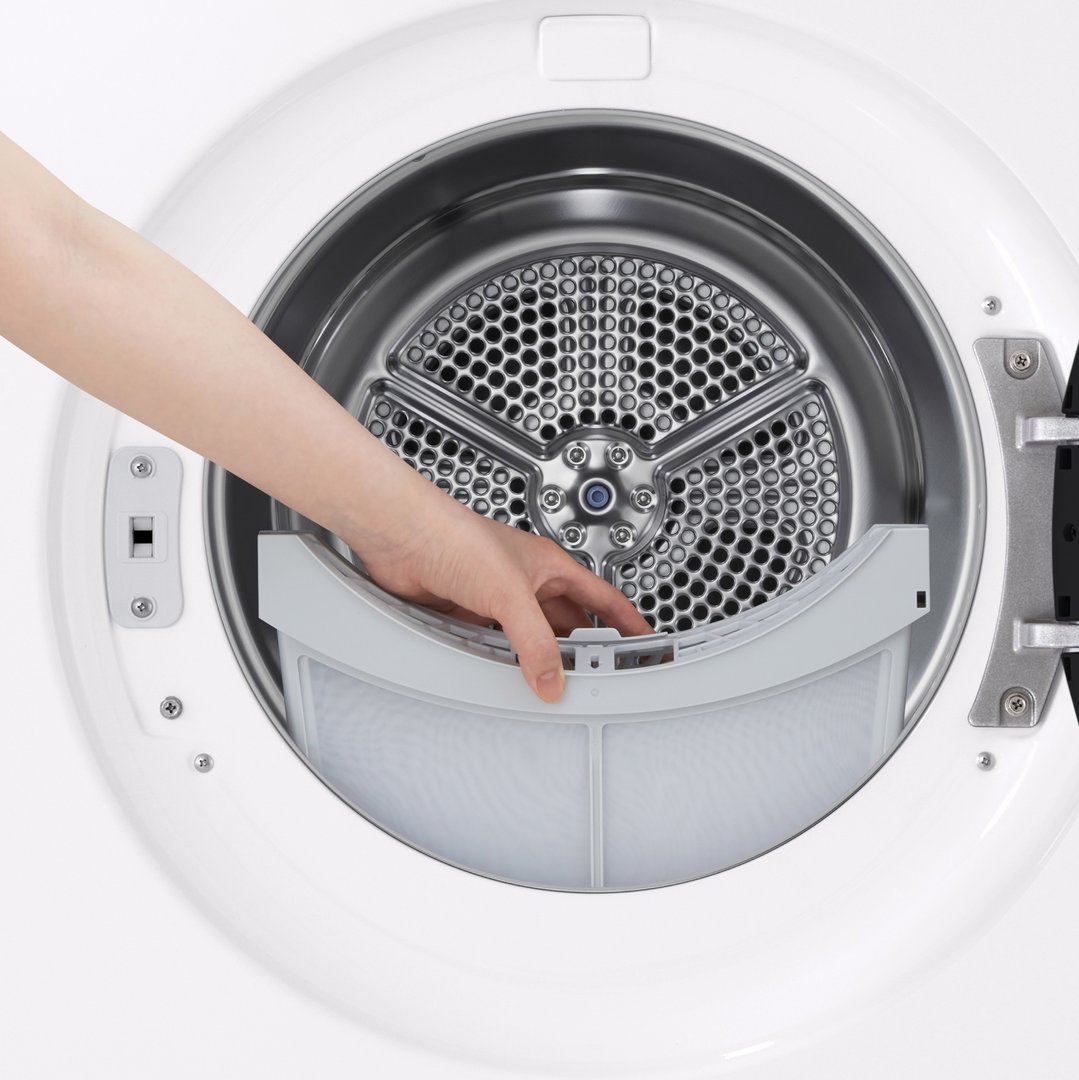 A hand removing the lint filter from inside a white dryer