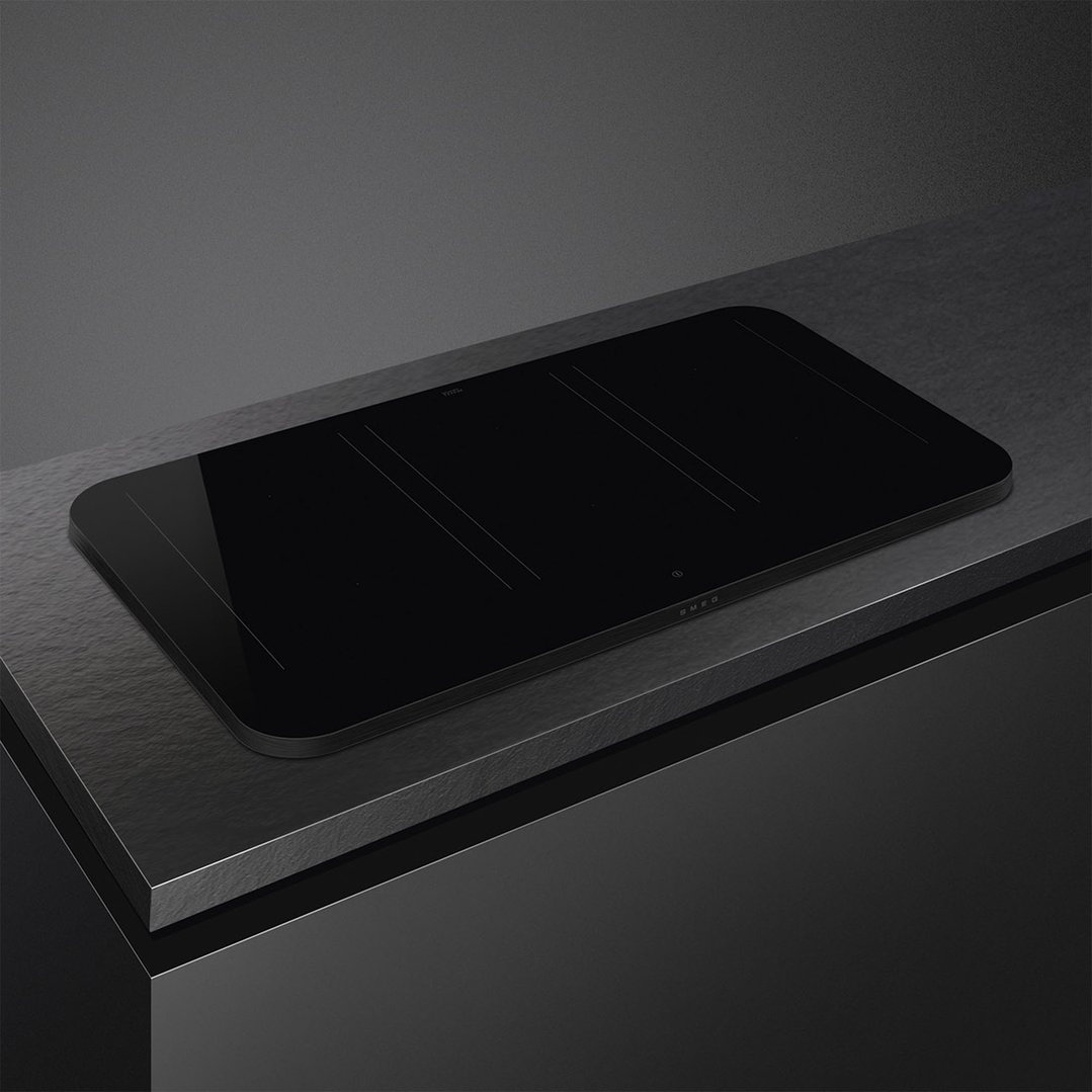 Black induction cooktop with controls on a dark countertop in a modern kitchen
