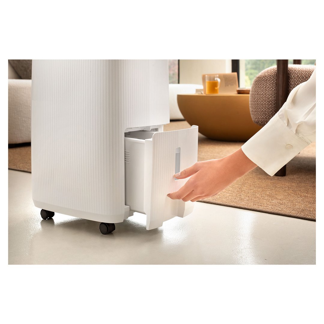 Hand pulling out the water tank from a white De'Longhi dehumidifier