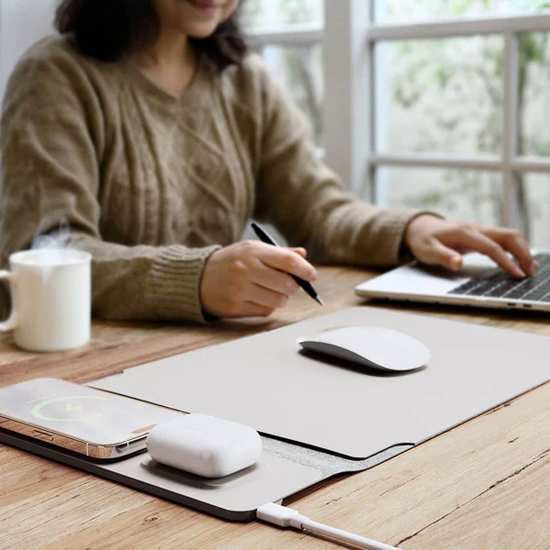 Woman working on a laptop with a wireless charging mat on a wooden desk